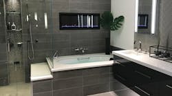 This contemporary suite has a heated towel rack and wall-mounted toilet. The vanity from the Furniture Guild has multi-purpose drawers that can be fitted with lights, dividers and electrical outlets as needed. Customers can view the suite in different intensities and colors of light.