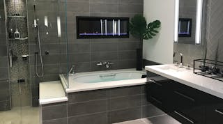 This contemporary suite has a heated towel rack and wall-mounted toilet. The vanity from the Furniture Guild has multi-purpose drawers that can be fitted with lights, dividers and electrical outlets as needed. Customers can view the suite in different intensities and colors of light.