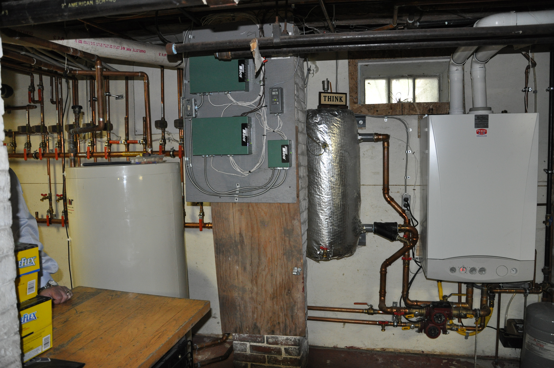 The mechanical room with wallhung boiler at right thermal storage tank at left and zone valve relays in the center