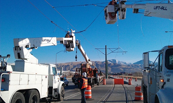 Contractors coordinate to set up electrical lines above light rail line