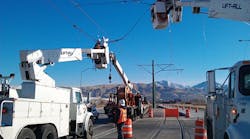 Contractors coordinate to set up electrical lines above light rail line.