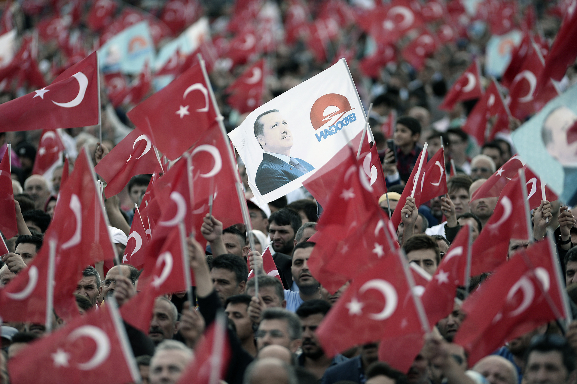 Supporters of Turkish President Tayyip Erdogan and Prime Minister and leader of the ruling Justice and Development Party AKP Ahmet Davutoglu wave national flags during a ceremony to mark the 562nd anniversary of the conquest of the city by Ottoman Turks on May 30 2015 in Istanbul Turkey