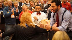 Nexstar member Tammy Ferris breaking through a board held by Keith Mercurio while Nexstar Training Manager Julian Scadden and the crowd cheer her on.