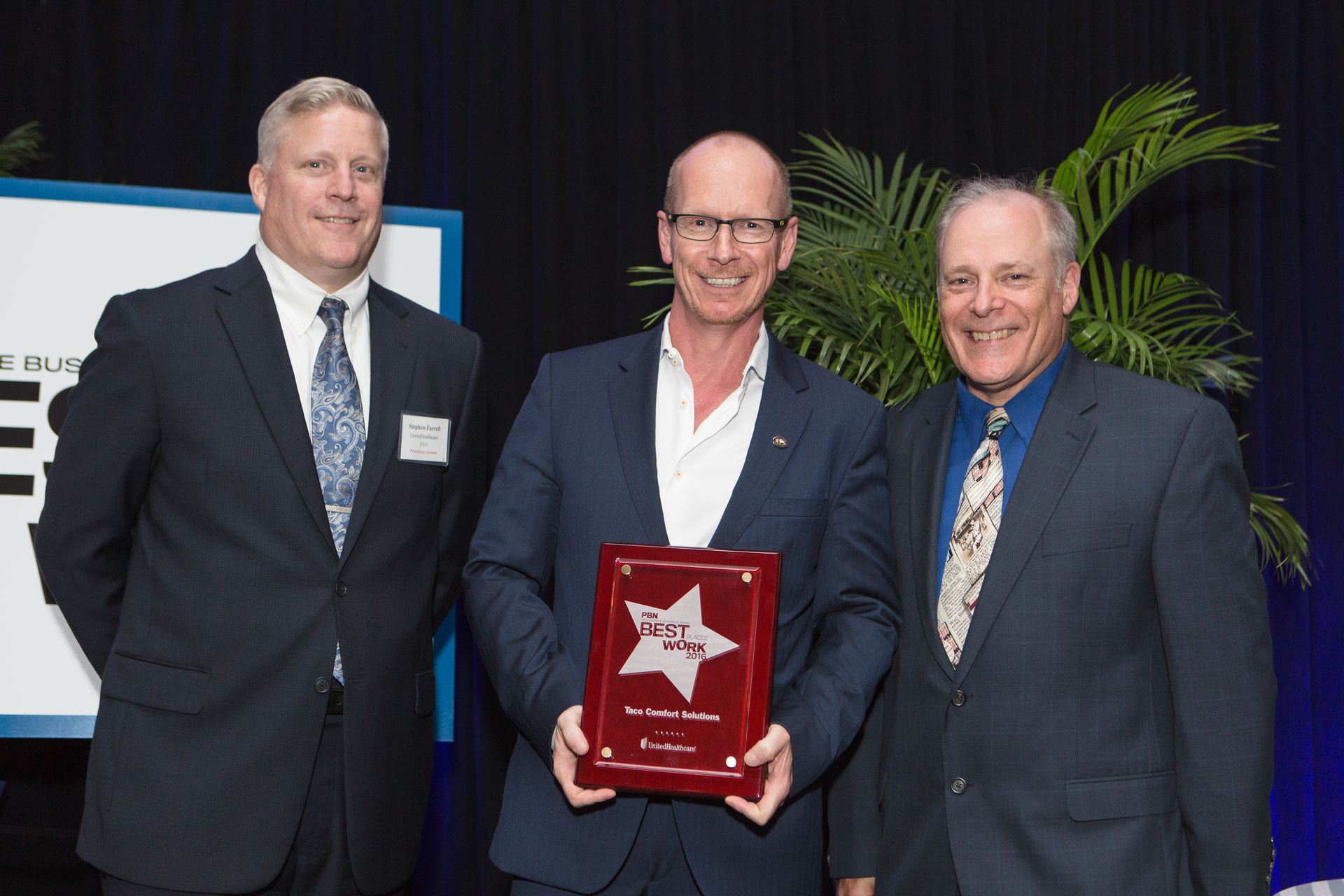Taco Comfort Solutions COO Wil VandeWiel holds the Best Places to Work in RI award at the event ceremony Flanking him left to right are Stephen Farrell CEO of UnitedHealthcare the Presenting Sponsor and Mark Murphy Editor of Providence Business News