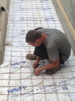 An ACS technician installing Uponor tubing for the snowmelt system.