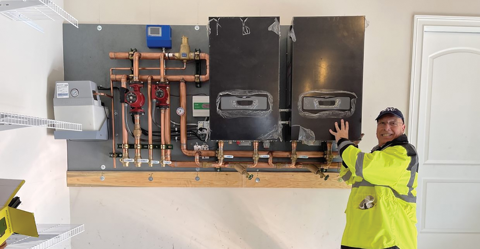 Jason Ridgeway with the prefabbed panel for the system, including HTC boilers, tekmar control and Grundfos circulators.