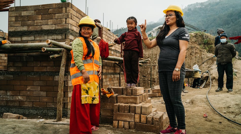 New homeowner Sabita T. taking a break on her job site with NIVAS Program Coordinator in Nuwakot, Nepal.