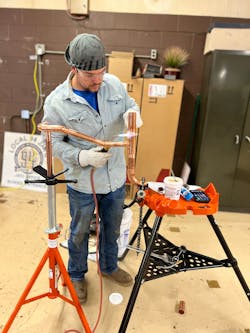 A tech soldering a copper joint. A tech soldering a copper joint.