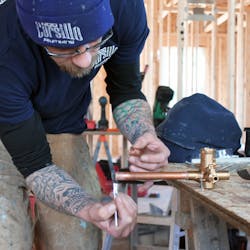 A technician applies flux to the end of a piece of pipe. A technician applies flux to the end of a piece of pipe.