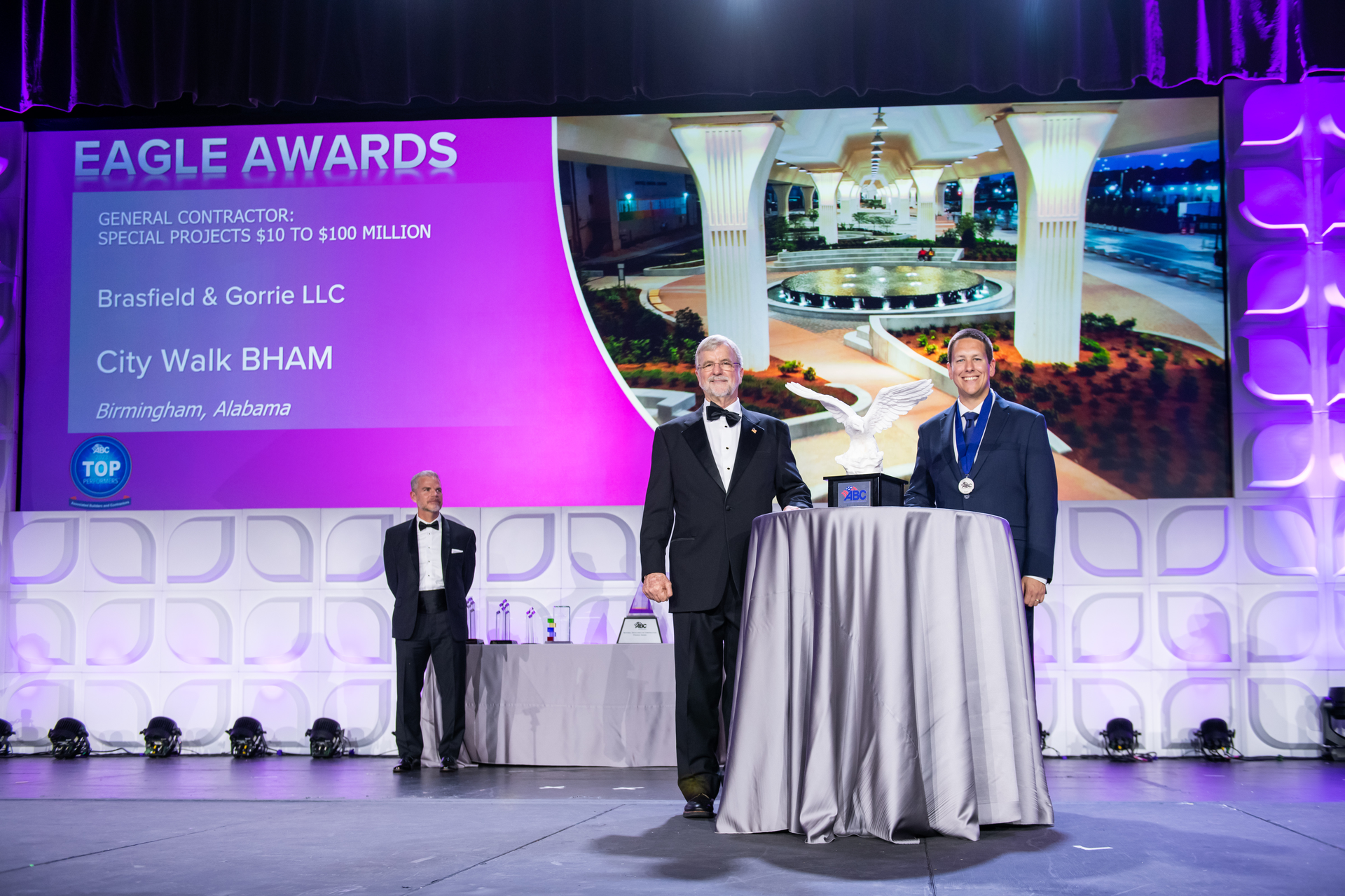 At the 2023 Eagle Awards, National Chair of the ABC Board of Directors Milton Graugnard (center) presents an award to Kyle McMullen of Brasfield and Gorrie while ABC Business Development Committee Chair Michael Barker (left) looks on.