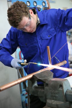 Student in plumbing professional training, working on copper.