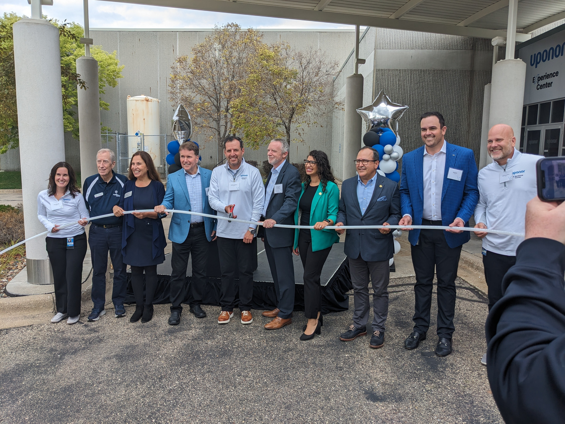 Uponor North America President Andres Caballero cuts the plastic pipe 'ribbon' to open the company's new Experience Center.