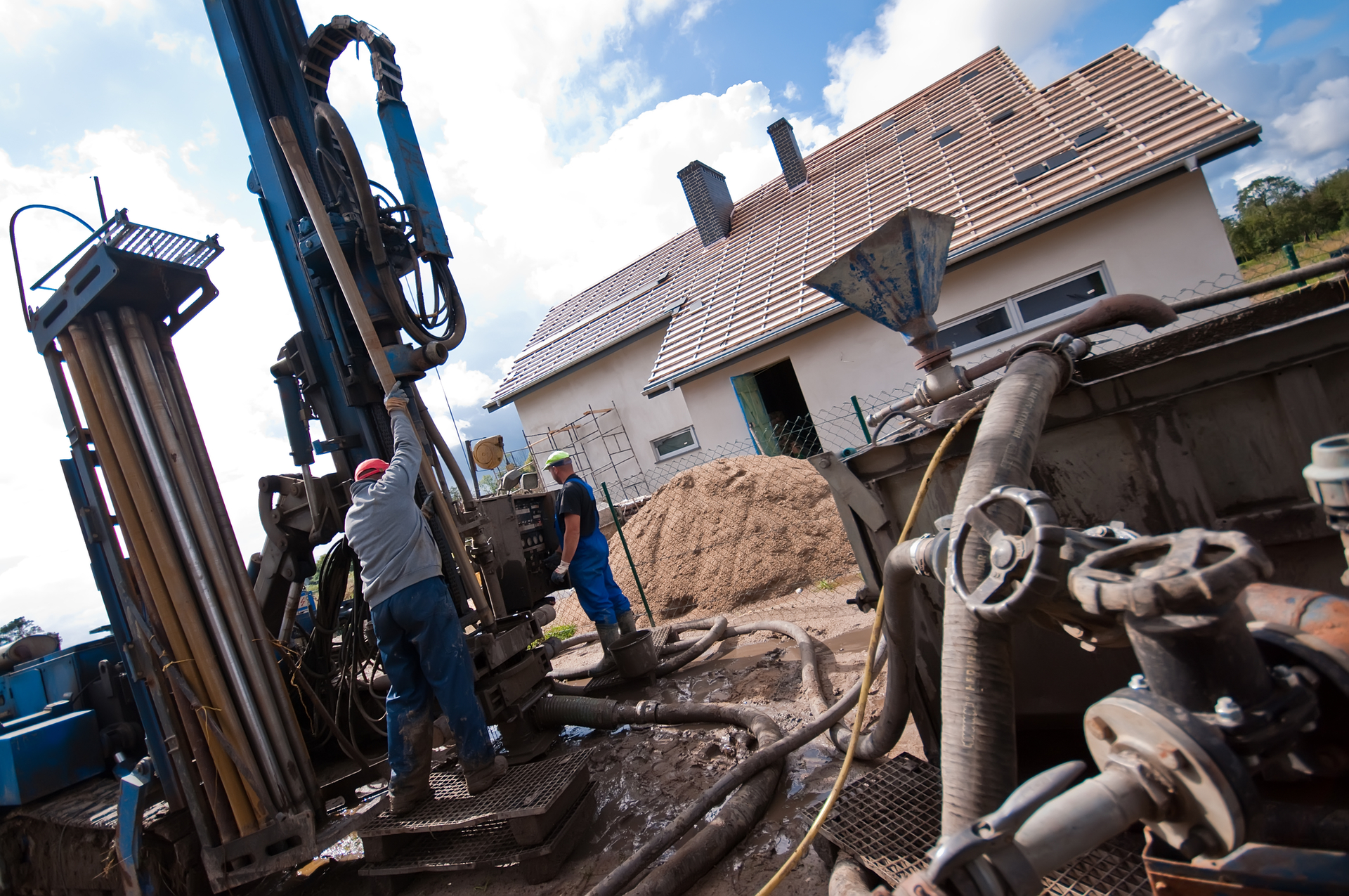 Two workmen drilling a residential geothermal field.