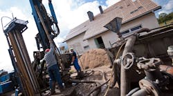 Two workmen drilling a residential geothermal field. Two workmen drilling a residential geothermal field.