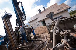 Two workmen drilling a residential geothermal field. Two workmen drilling a residential geothermal field.