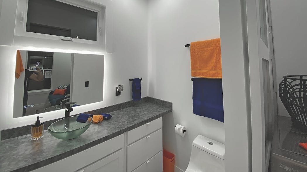 The bathroom includes a full-size shower, a sink and the Saniflo Rear Discharge Toilet.