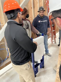 Workers carrying a Geberit in-wall carrier to a module. Workers carrying a Geberit in-wall carrier to a module.