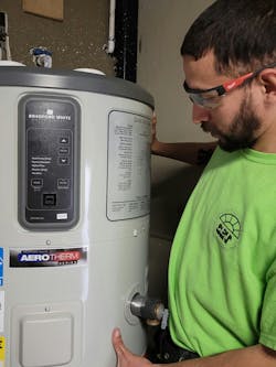 A trainee with one of the donated heat pump water heaters.