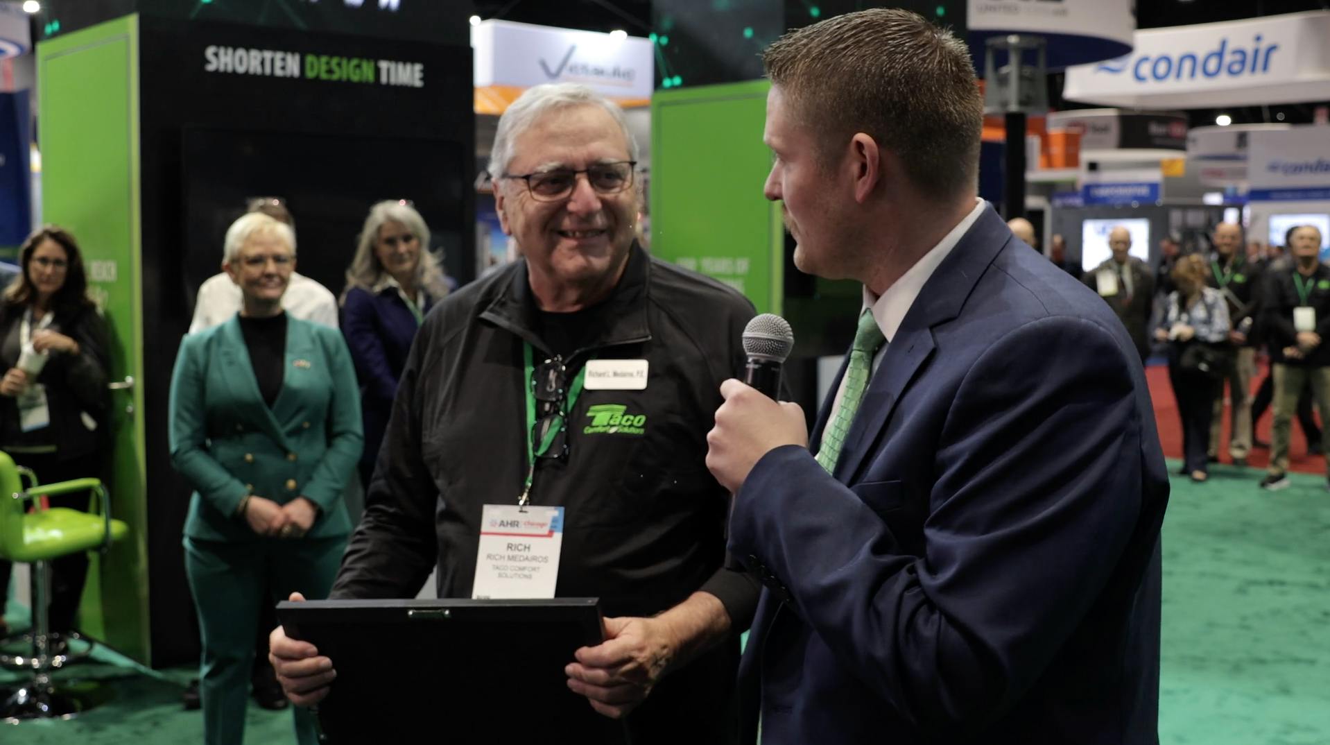 Ben White, Program Manager, Business Operations of Taco Comfort Solutions presents Richard Medairos with the Dan Holohan Lifetime Contribution to Comfort Award at AHR Expo 2024.