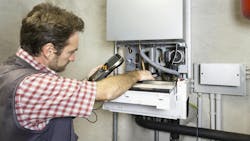 Plumber repairing a condensing boiler. Plumber repairing a condensing boiler.