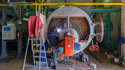 A worker repairing a boiler. A worker repairing a boiler.