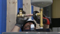 A competitor in the plumbing competition installs a water heater. A competitor in the plumbing competition installs a water heater.