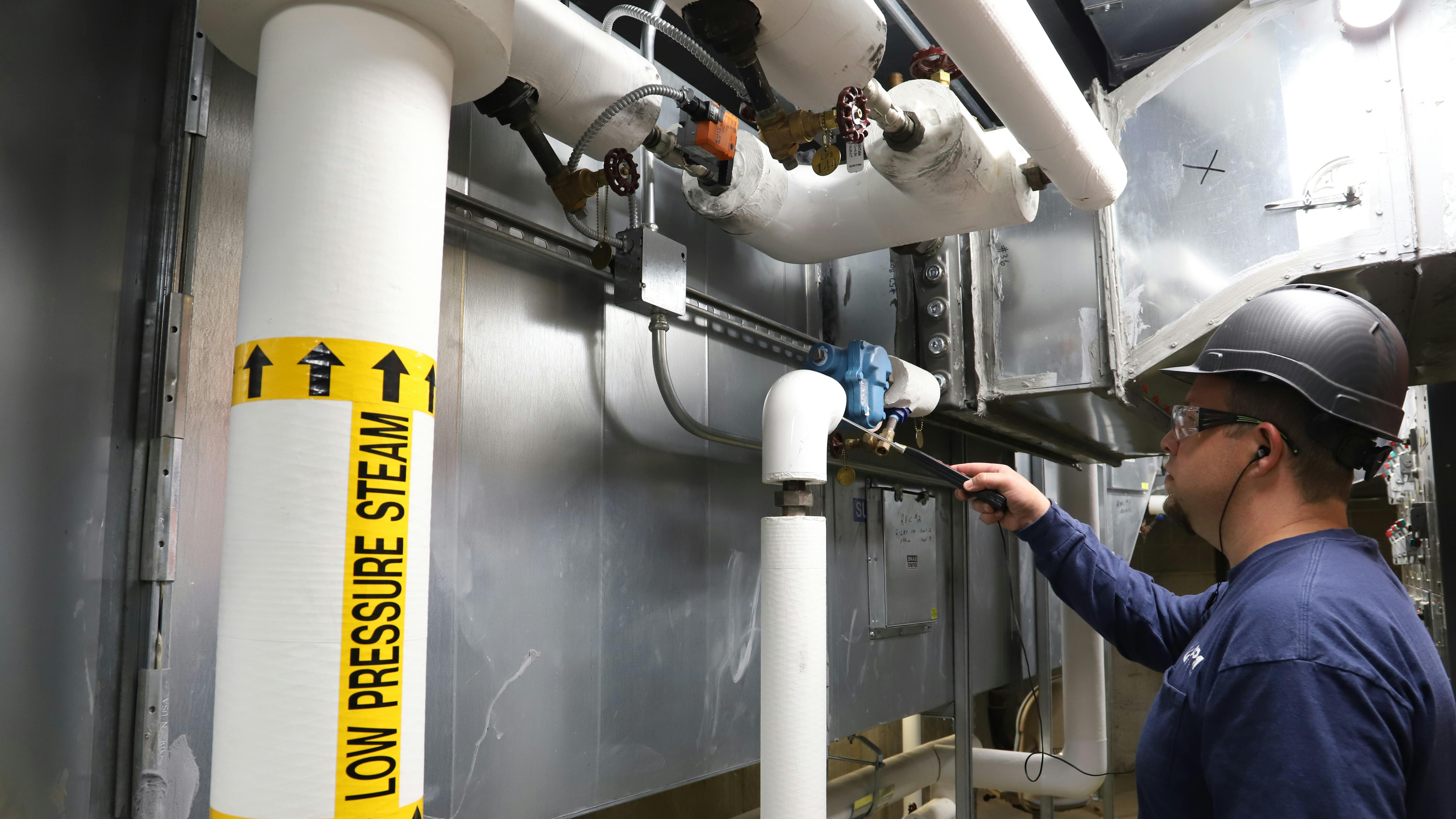 An APM technician inspects a steam trap.