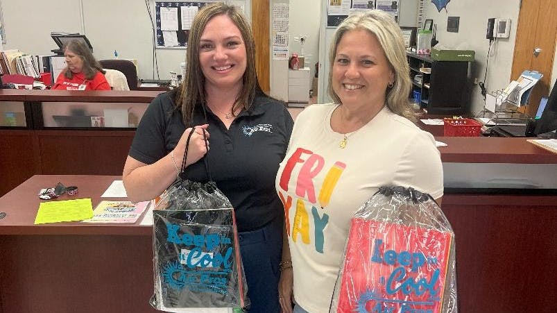 Two Air Pros USA employees at Pembroke Pines Elementary with bags of school supplies.