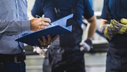 Unrecognizable owner going through reports with two workers in a warehouse. Unrecognizable owner going through reports with two workers in a warehouse.