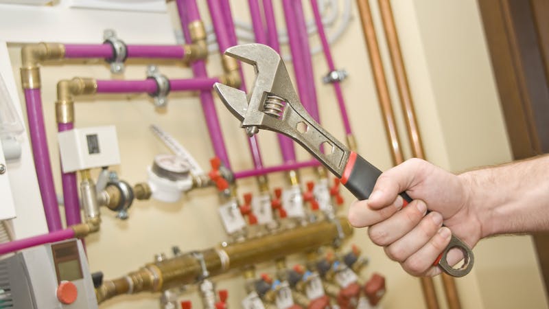 Servicing heating and water systems. Hand with adjustable wrench.