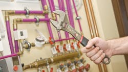 Servicing heating and water systems. Hand with adjustable wrench. Servicing heating and water systems. Hand with adjustable wrench.
