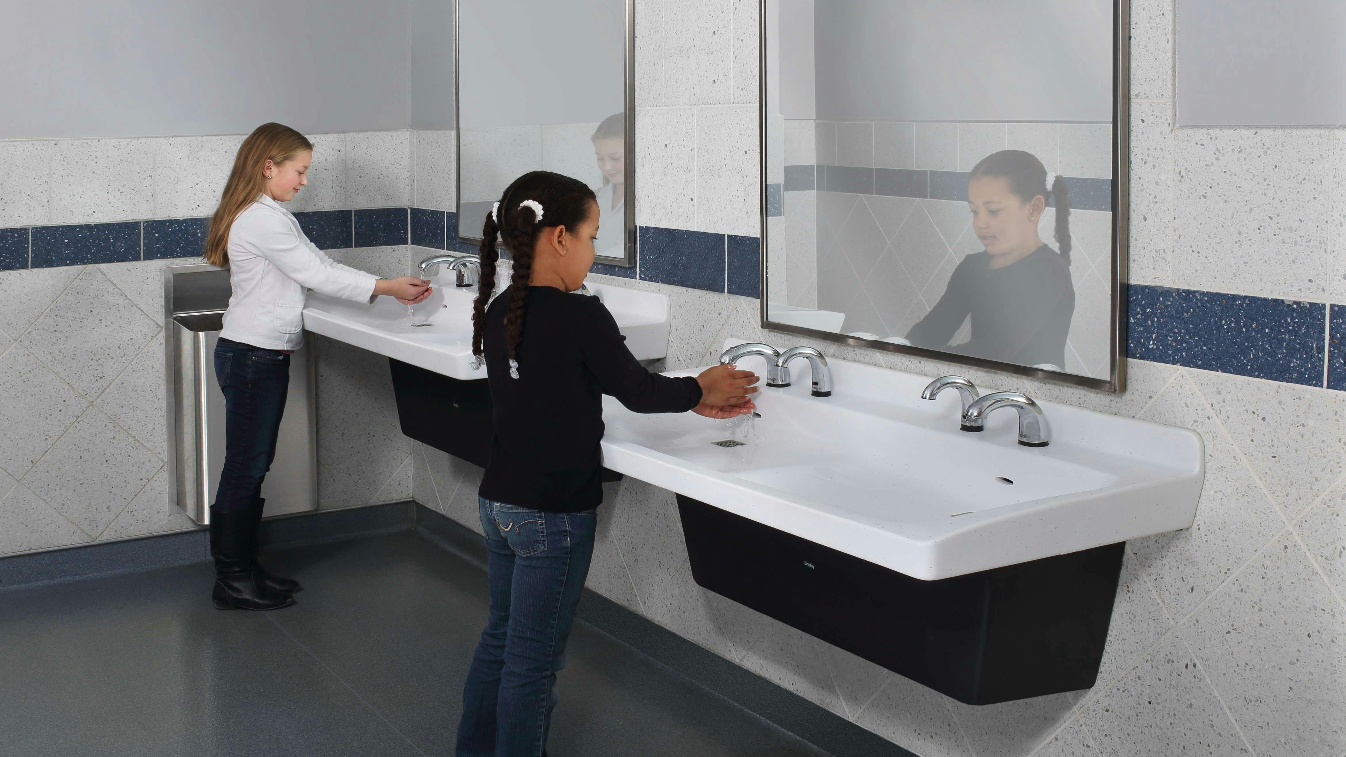 girls washing their hands in a commercial restroom