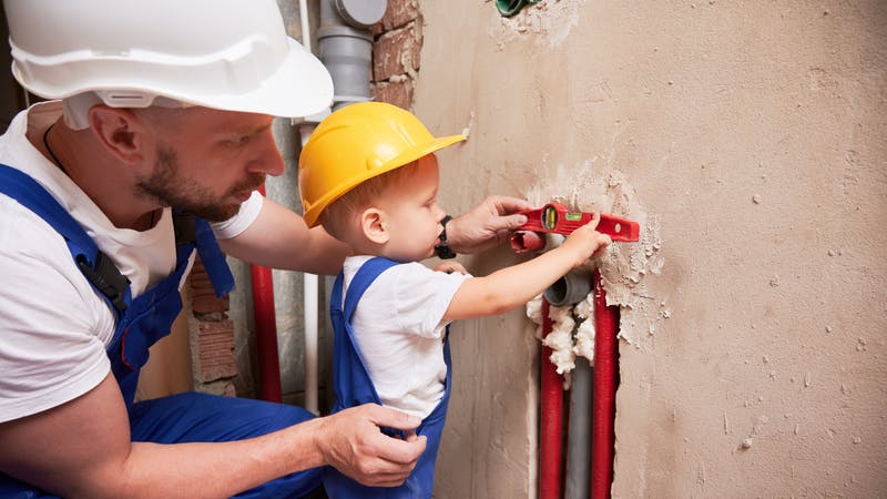 Father and son installing plumbing pipe system at home.