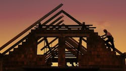 Construction worker working with house wooden roof against sunset sky Construction worker working with house wooden roof against sunset sky
