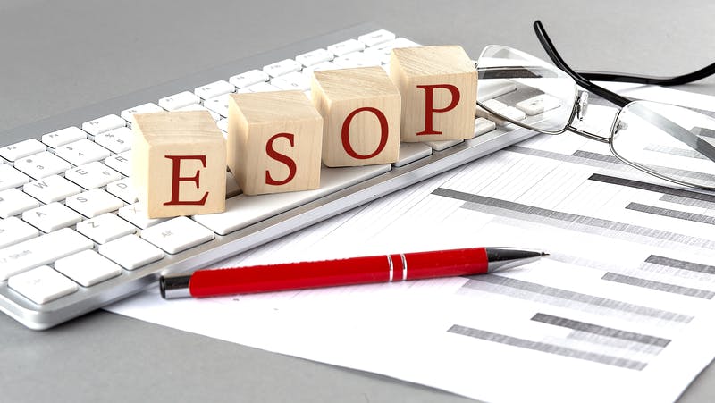 ESOP written on a wooden cube on the keyboard with chart on grey background