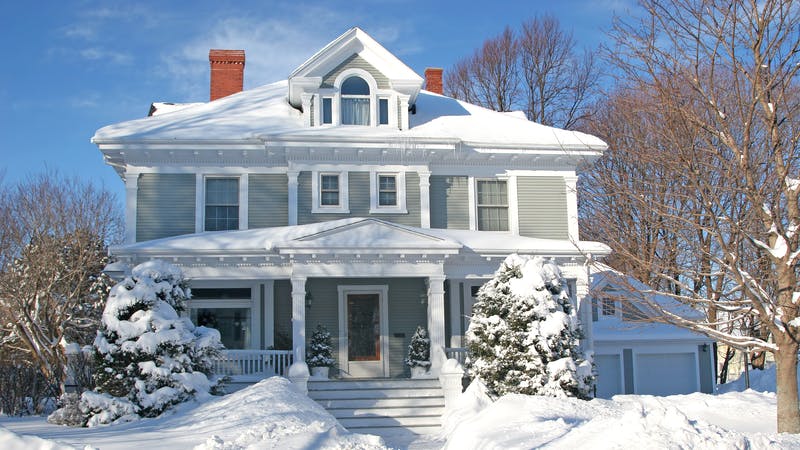 The front of a large older home covered in deep snow.