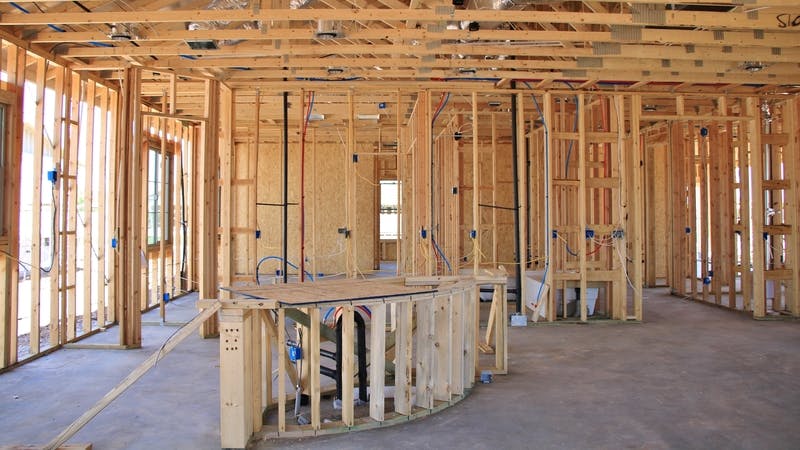 An interior view of a new home under construction with exposed wiring and kitchen island