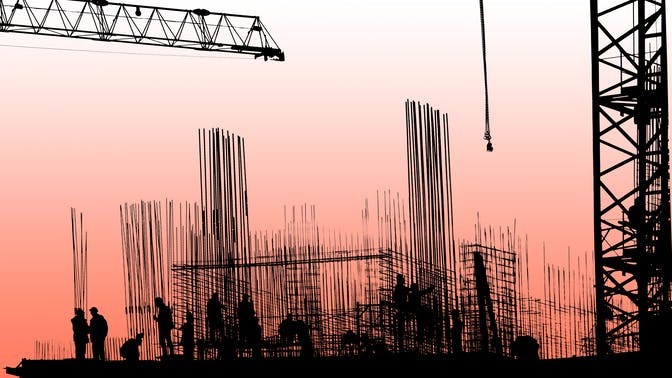 The silhouettes of construction workers, construction equipment and elements of a building