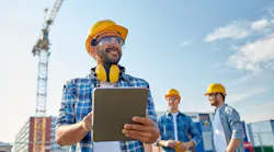 Builder in hardhat with tablet pc at construction site. Builder in hardhat with tablet pc at construction site.