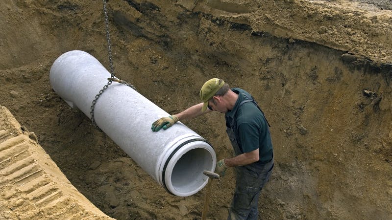 Worker laying in new sewer pipe.