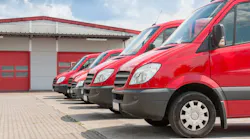 Row of red delivery and service cars in front of a factory and warehouse distribution plant Row of red delivery and service cars in front of a factory and warehouse distribution plant