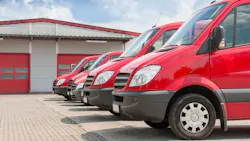 Row of red delivery and service cars in front of a factory and warehouse distribution plant Row of red delivery and service cars in front of a factory and warehouse distribution plant