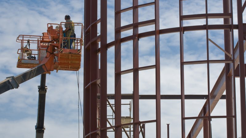 Workers on lifts at a steel building construction site