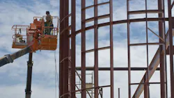 Workers on lifts at a steel building construction site Workers on lifts at a steel building construction site