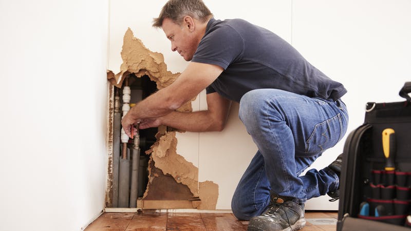 Plumber fixing burst pipe