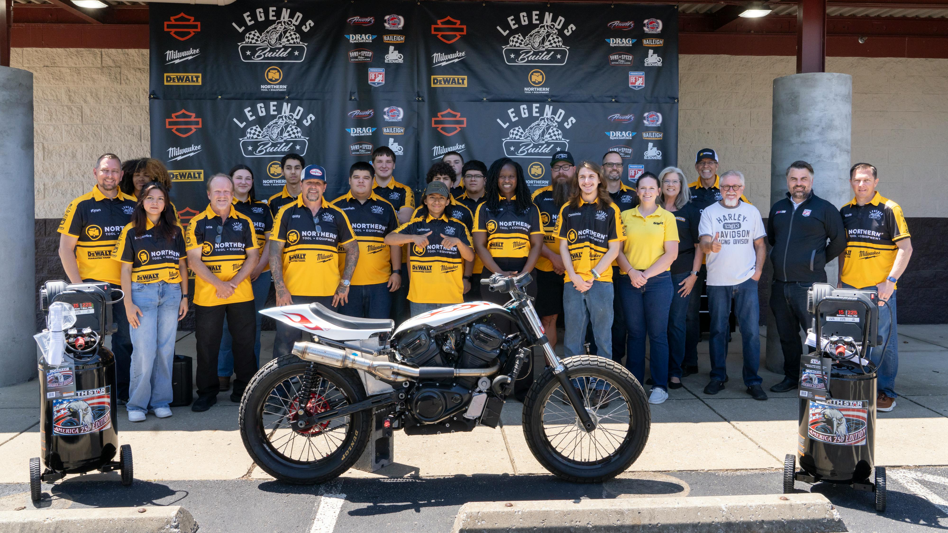 A group photo of the build team, with one of the converted motorcycles.