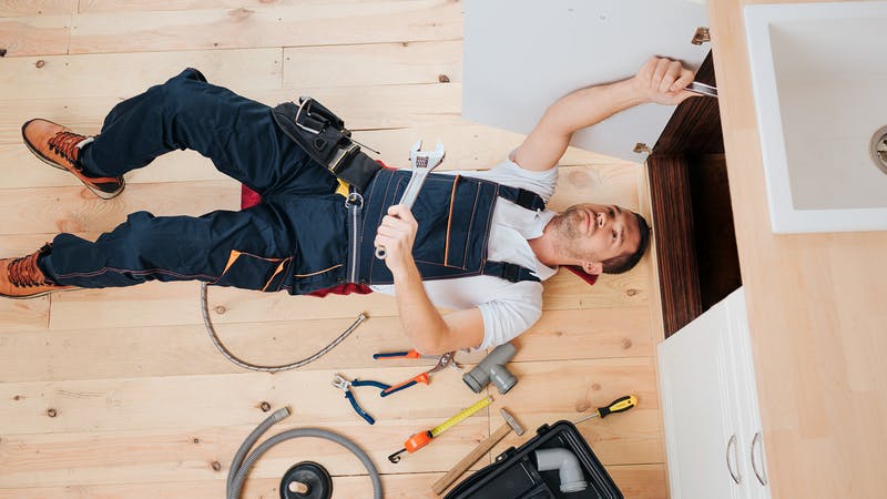 plumber at work under a sink