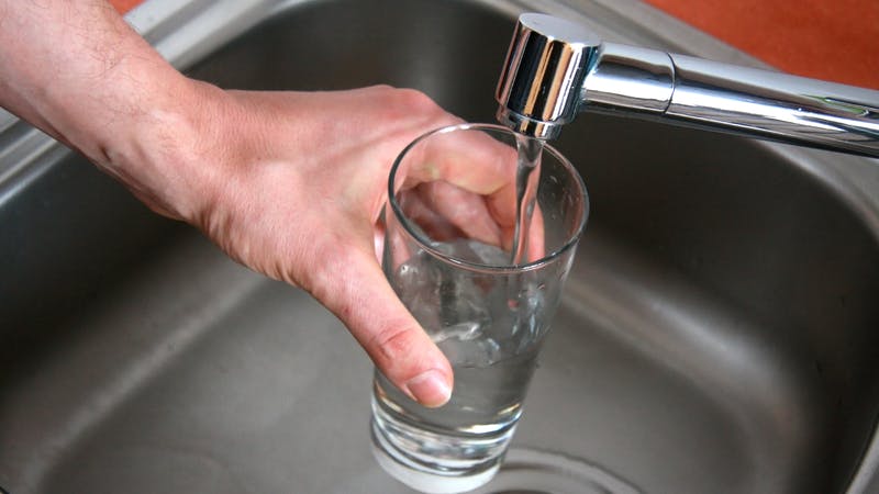 hand holding a glass of water at a faucet