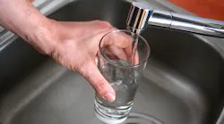 hand holding a glass of water at a faucet