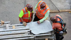 Three construction workers looking at construction drawing blueprint